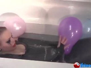 Latexen klädd husmor med ballonger i en badkar